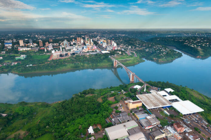 Aerial view of the Paraguayan city of Ciudad del Este and Friendship Bridge, connecting Paraguay and Brazil through the border over the Parana River, with Brazilian customs and immigrations facilities in the foreground.