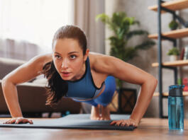 Beautiful young sports lady doing push ups while workout at home