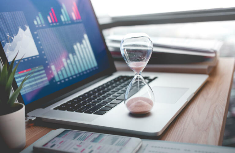 Business concepts with businessman holding hourglass with graph chart on computer laptop.For investment analysis,Waiting to sucess ideas
