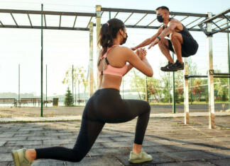 Kalistenika: Ko za telovadbo ne potrebuješ uteži Caucasian man and mixed race girl in protective masks training on sport ground during coronavirus pandemic, widescreen. Healthy lifestyle and street sport during quarantine concept