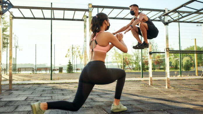 Caucasian man and mixed race girl in protective masks training on sport ground during coronavirus pandemic, widescreen. Healthy lifestyle and street sport during quarantine concept