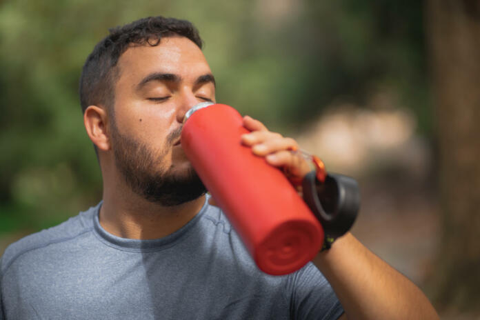Hiker drinking water from his red ecologic aluminum watter bottle