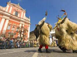 Ljubljana, Slovenia - March 5, 2011: Group of kurents are dancing and jumping, big bells, which are tied by the waist, are ringing loud. Viewers around them take pictures and laugh. Kurenti, according to folk tradition, chase away the winter and the cold.