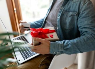 7 tehnoloških daril za valentinovo Man using laptop computer and credit card, ordering gifts for Valentines day, Womans Day, Christmas. Shopping online during holidays
