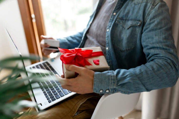 Man using laptop computer and credit card, ordering gifts for Valentines day, Womans Day, Christmas. Shopping online during holidays