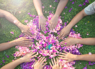 Veliki ženski krog »Odkrivanje notranje moči in preseganje ovir« Many hands touch each other on a bed of flowers