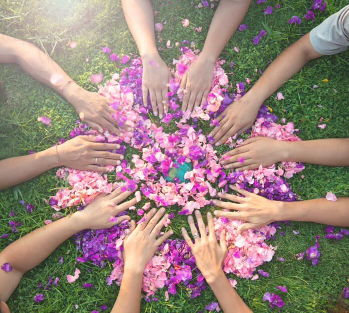 Many hands touch each other on a bed of flowers