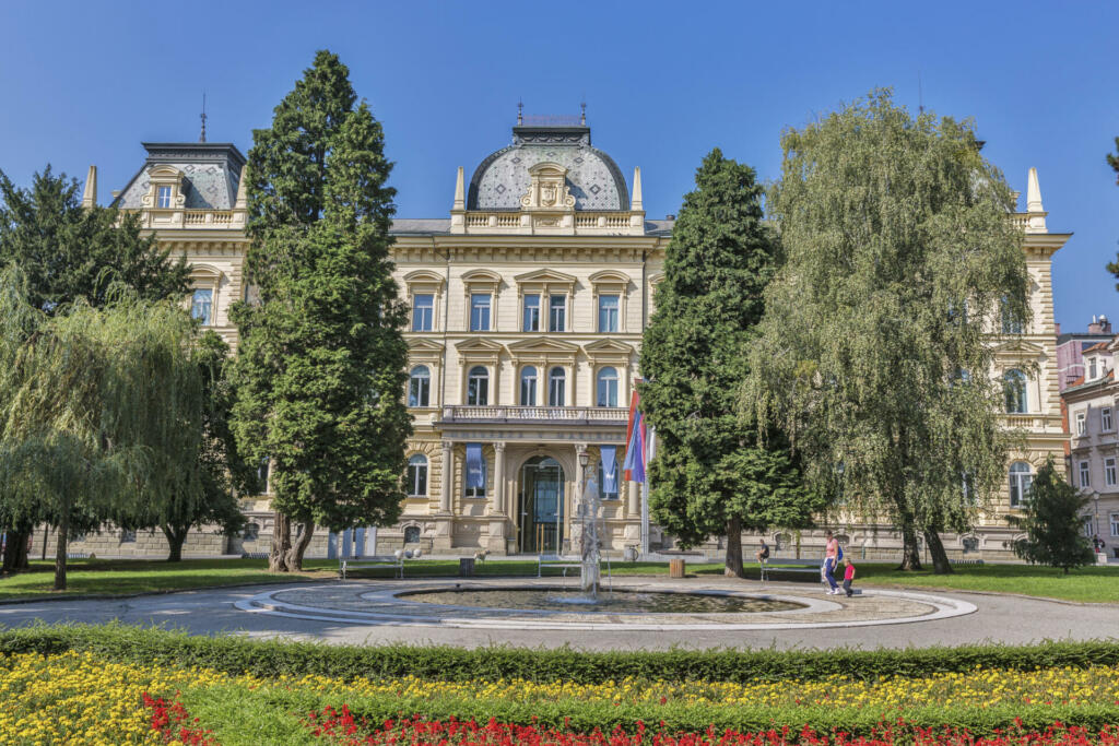 Maribor, Slovenia - September 13, 2015: Unrecognized people walk in front of Headquarters of the University of Maribor with park and fountain.