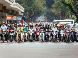 Motorcycles got traffic jam on the road with green trees in background at Hanoi, Vietnam.