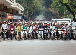 Izpit za moped in električni skiro: Kaj moraš vedeti? Motorcycles got traffic jam on the road with green trees in background at Hanoi, Vietnam.