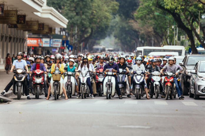 Motorcycles got traffic jam on the road with green trees in background at Hanoi, Vietnam.