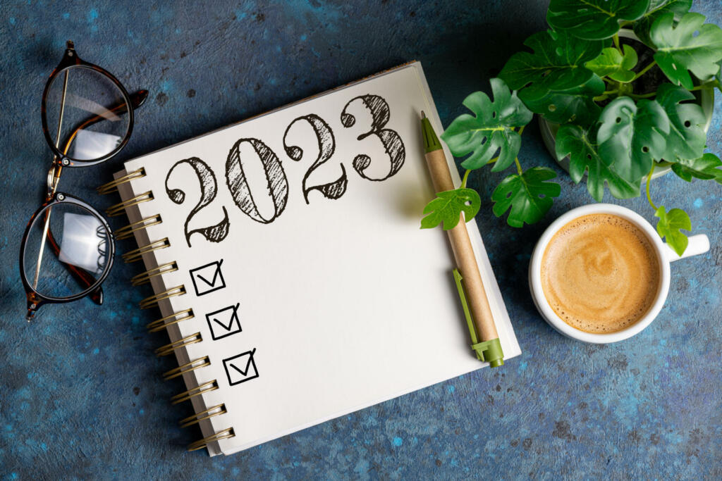 New year resolutions 2023 on desk. 2023 resolutions list with notebook, coffee cup on table. Goals, resolutions, plan, action, checklist concept. New Year 2023 template, copy space