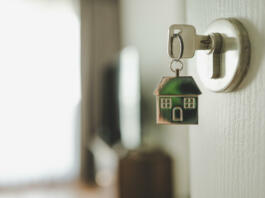 Open the door and door handle with a key and a keychain shaped house. Property investment and house mortgage financial real estate concept