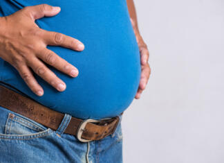 Znanost o hujšanju: Zmanjšanje števila kalorij je učinkovitejše kot postenje Overweight or fat adult man in very tight jeans on a gray background. Healthcare, medicine concept.