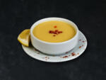 Red lentil soup in white plate on black stone background.