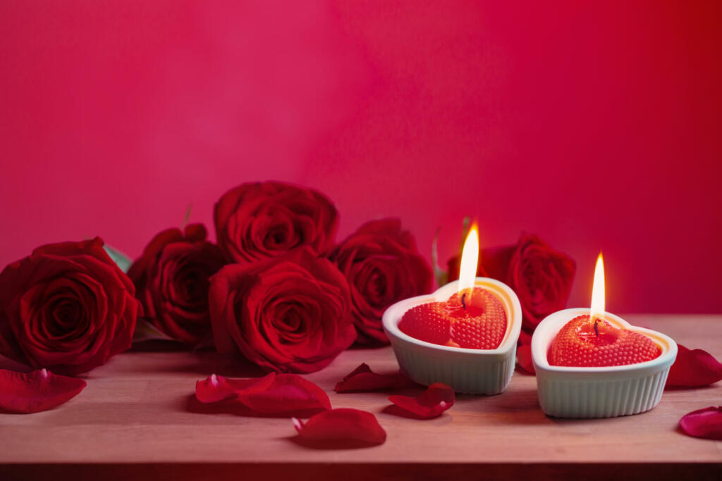 red roses with burning candles on pink background