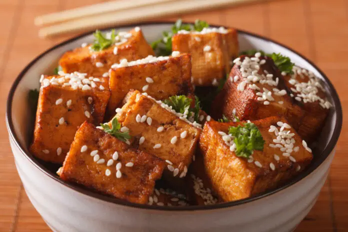 Stir fry tofu with sesame seeds and herbs in a bowl close-up. horizontal