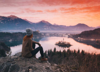 Predstavniki Mladinskega sveta z ministrom Brežanom o vlogi mladih v urejanju prostora Travel Slovenia, Europe. Woman looking on Bled Lake with Island, Castle and Alps Mountain on background. Top view. Bled Lake one of most amazing tourist attractions. Sunset winter nature landscape.