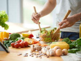 Vegetarian man mixing vegetable salad in bowl