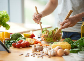 Začni kuhati zdravo in zaužij življenje Vegetarian man mixing vegetable salad in bowl