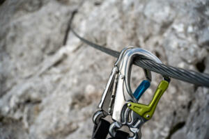 Via ferrata set with coloured carabiners hangs on a wire rope on a rocky mountain. close up