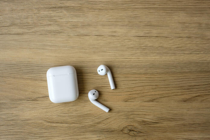 White wireless earphone or headphones on table for using with smartphone. Technology concept