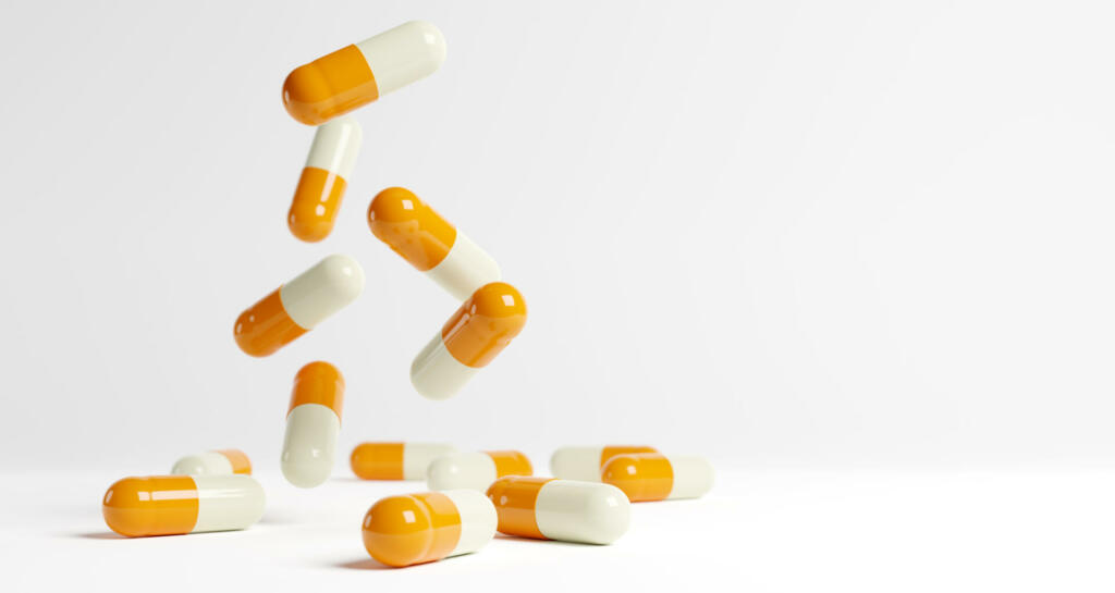 Yellow and white medical capsules falling down on the blue background. 3D render. 3D illustration.