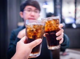 Young couple with glasses of refreshing cola with ice in restaurant, Two glasses of cola with ice