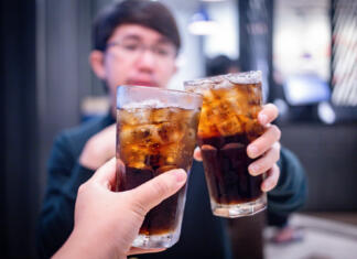Pitje gaziranih pijač lahko poveča velikost testisov in proizvodnjo testosterona Young couple with glasses of refreshing cola with ice in restaurant, Two glasses of cola with ice