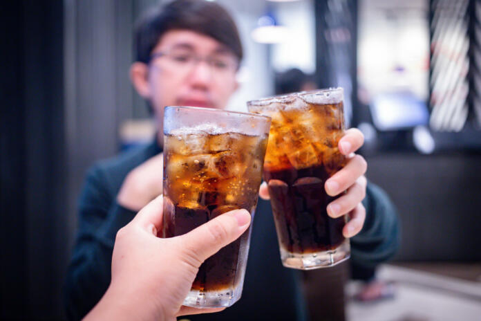 Young couple with glasses of refreshing cola with ice in restaurant, Two glasses of cola with ice