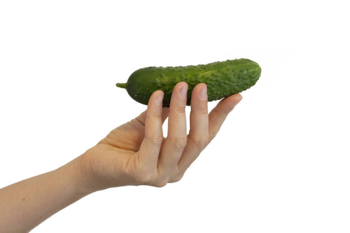 Young woman holding a cucumber. Green tasty vegetable in hand. Healthy diet food. Natural ingredient for dishes and salad. Photo isolated on white background