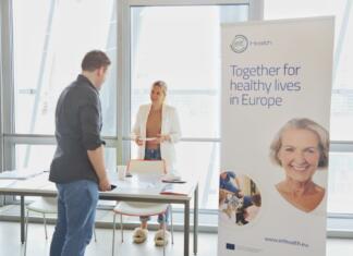 Te zanima podjetništvo na področju zdravstva? Preveri te programe! Moški in ženska se pogovarjata prek mize, zraven je promocijski pingvin