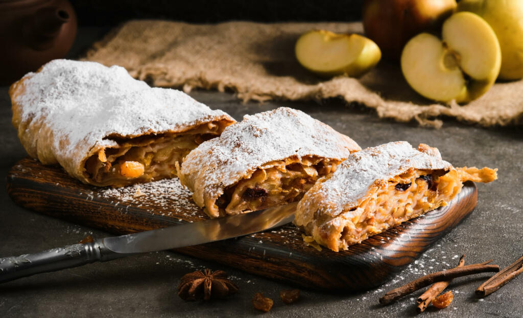 Apple pie - strudel or apfelstrudel, sliced "u200b"u200bpie with apples and spices on a gray table, close-up, selective focus. Traditional pies of European cuisine