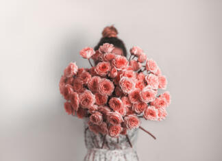 Kako je nastal osmi marec, dan žena? Bouquet in female hands. Bunch of Living Coral roses. Color of year 2019 Living Coral concept.