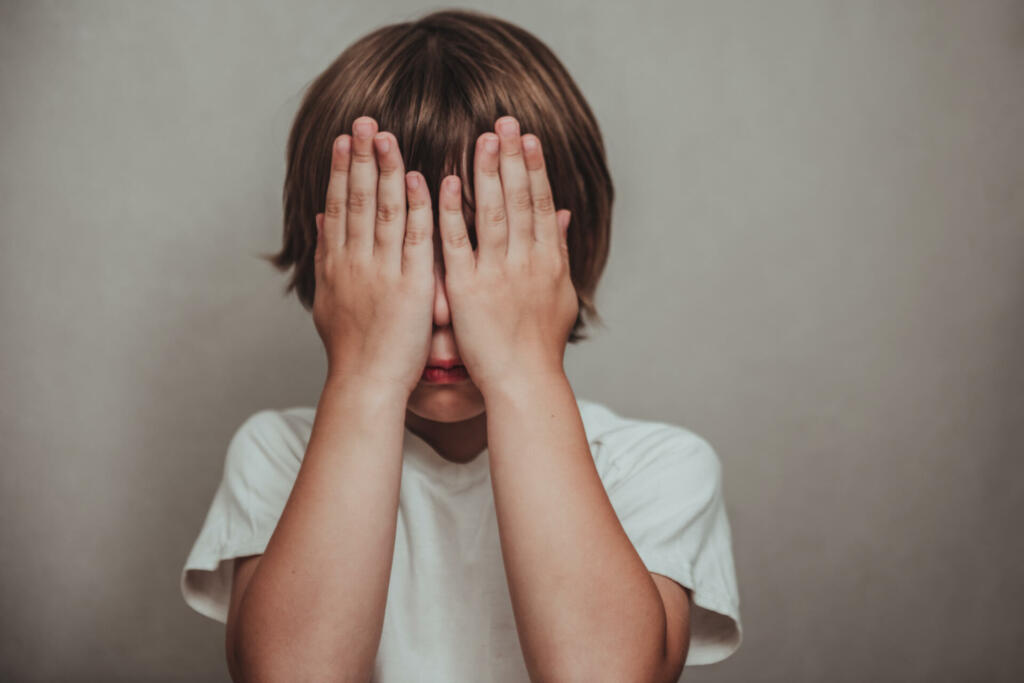 Boy crying covered his face with his hands. Stressed child. Domestic Family violence and aggression concept violence