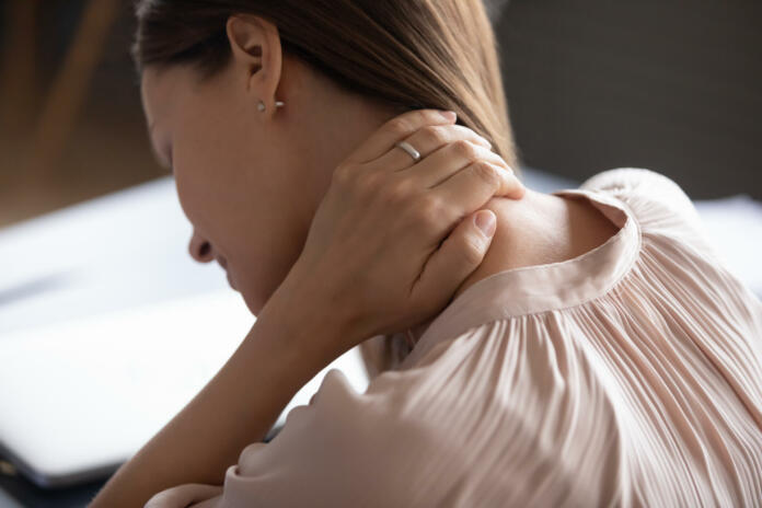 Close up exhausted woman touching massaging tensed neck muscles, feeling unwell after long hours sedentary work, uncomfortable chair, incorrect posture, young female suffering from pain, ache