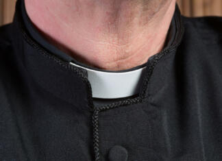 Nov škandal katoliške cerkve, ki odmeva po svetu Closeup of the neck of a priest wearing a black shirt with cassock and white clerical collar