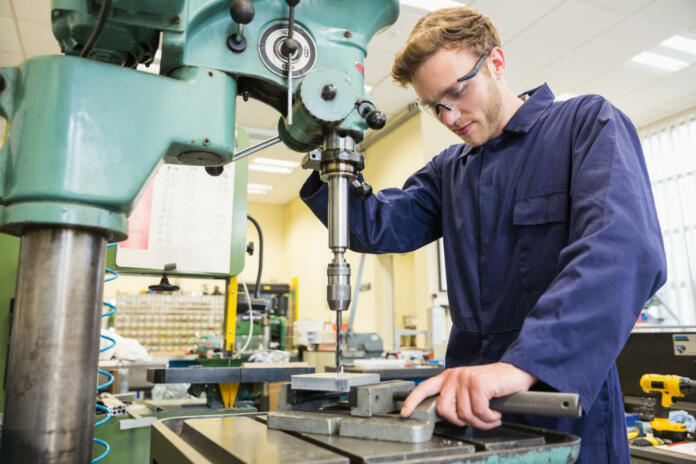 Engineering student using large drill at the university