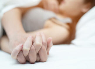 Kolikokrat na mesec bi morali ejakulirati? Feeling on hands of passion couple having sex. two Lovers couple Holding hands under blanket white sheets on the bed with lust and making love. concept having sexual romantic moments.