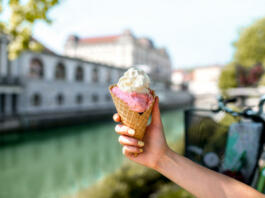 Female hand holding ice cream cone on the water chanal and bicycle on the background in Ljubljana city. Slovenian street food
