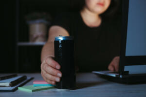 Focused woman holding and energy drink in the night. Deadline project, overworking, freelance worker