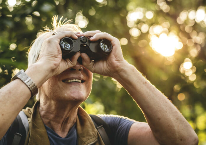 Mature man watching birds through binoculars