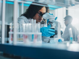 Medical Science Laboratory: Portrait of Beautiful Black Scientist Looking Under Microscope Does Analysis of Test Sample. Ambitious Young Biotechnology Specialist, working with Advanced Equipment
