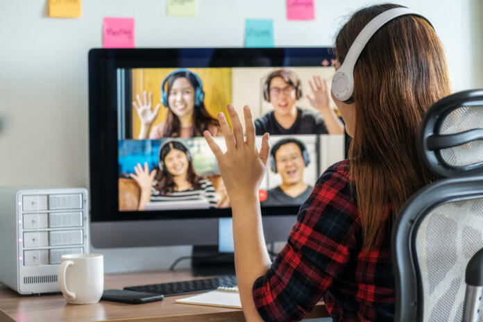 Online meeting, Social distancing and new normal concept, Rear View of Asian Business woman say hello with teamwork colleague in video conference when Coronavirus outbreak