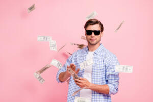 Portrait of his he nice cool trendy content attractive handsome candid guy wearing checked shirt throwing money flying in air party wealth isolated over pink pastel background