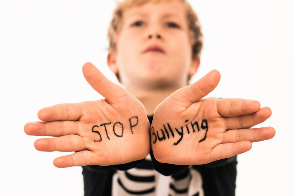 Scared boy shows his hands with the slogan Stop Bullying, isolated on white.