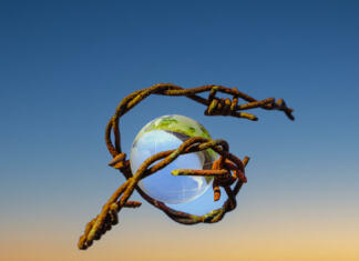 Države s povečanim tveganjem za pranje denarja in financiranje terorizma (2023) The concept of symbolism. On a blue sky is a glass globe, which is surrounded by rusty barbed wire