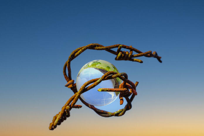 The concept of symbolism. On a blue sky is a glass globe, which is surrounded by rusty barbed wire