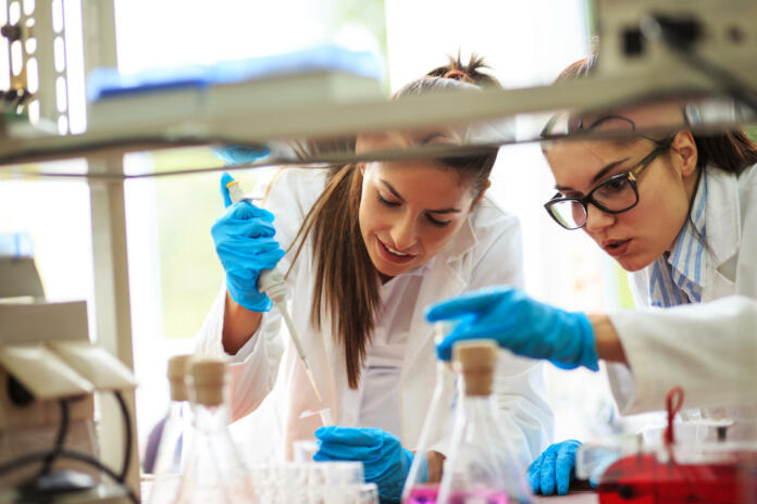 Two young female scientist doing experiments in lab.