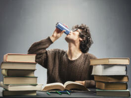 Young man drinking energy drink while studying. College student concept. Energizing before learning.